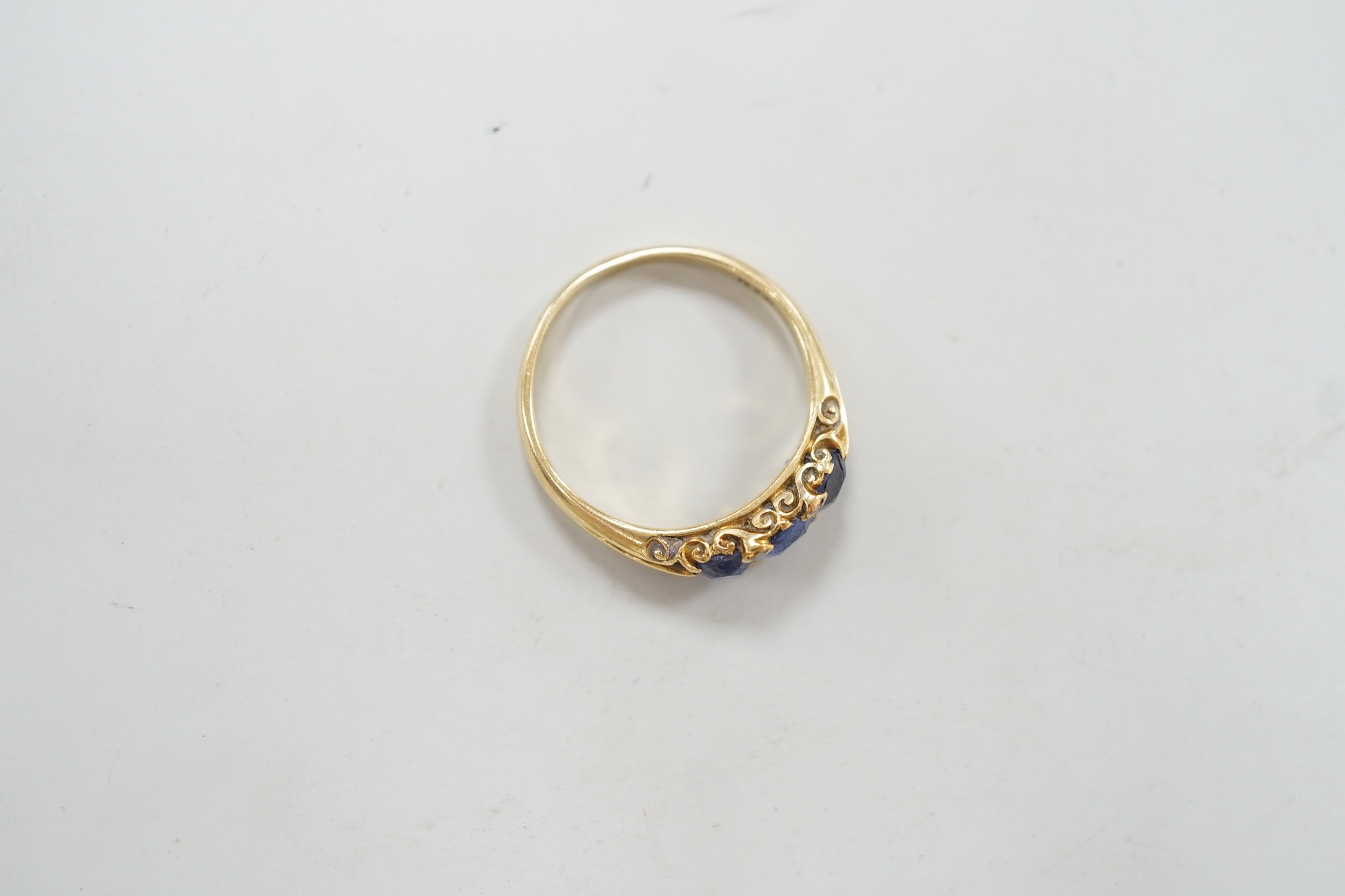 An early 20th century 18ct and three stone sapphire set half hoop ring, with diamond chip spacers, size Q, gross weight 4.2 grams.